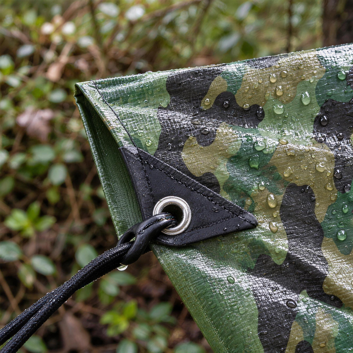 Close-up of the camouflage tarpaulin reinforced corner patch, eyelet and bungee with the green reverse