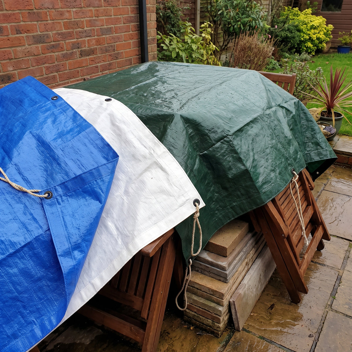 200gsm heavy duty waterproof tarpaulins in blue, white and green covering garden furniture on a UK patio