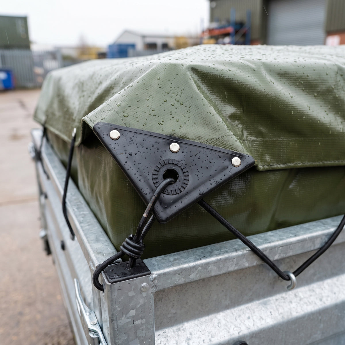 Close-up of the three-rivet corner reinforcement and eyelet on a 560gsm PVC tarpaulin with a bungee cord